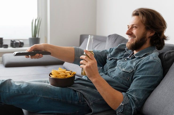 Man enjoying high-quality IPTV streaming with drink while relaxing